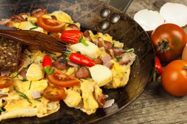 Jambon ve biber Taze karıştırılmış yumurta üzerinde çelik bir tavada biber. Geleneksel besleyici bir kahvaltı. Kalorili yemek.