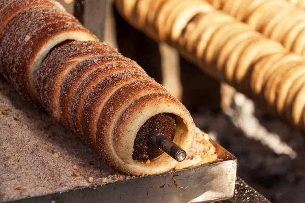 Trdelnik - traditional national czech street desert, baking on the street. Preparation of a sweet snack on the grill. — Stock Photo, Image