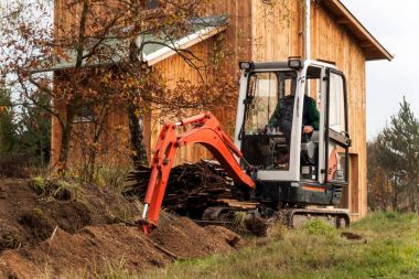 Mini Ekskavatör inşaat sitesinde. Bir forest yakınındaki müstakil bir ev inşaatı.