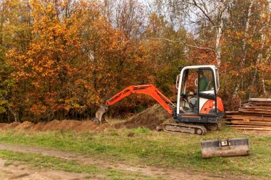 Mini Ekskavatör inşaat sitesinde. Bir forest yakınındaki müstakil bir ev inşaatı.