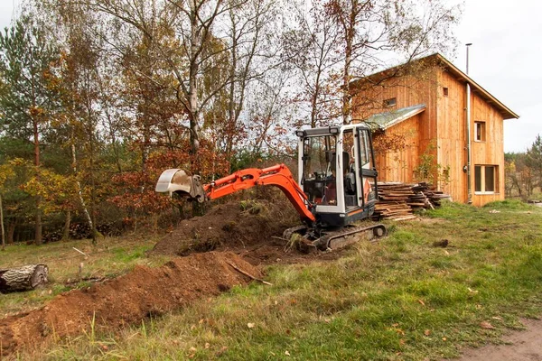 Mini Ekskavatör inşaat sitesinde. Bir forest yakınındaki müstakil bir ev inşaatı.