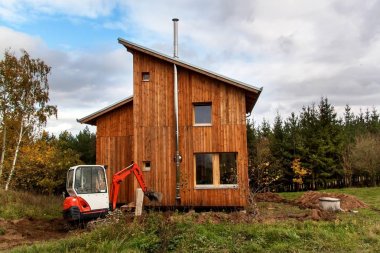 Mini Ekskavatör inşaat sitesinde. Evin çevresinde arazi Ekskavatör düzenler.