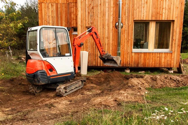 Mini koparki na budowie. Koparka reguluje terenu wokół domu. — Zdjęcie stockowe