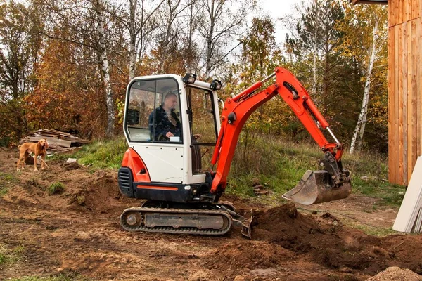 Mini koparki na budowie. Koparka reguluje terenu wokół domu. — Zdjęcie stockowe