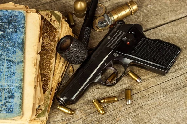 Pistolet et vieux livre. Un roman policier. Tuyau de tabac en bois. Pistolets et cartouches sur la table . — Photo