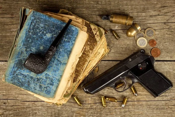 Gun and old book. Detective novel. Wooden tobacco pipe. Pistols and cartridges on the table. — Stock Photo, Image