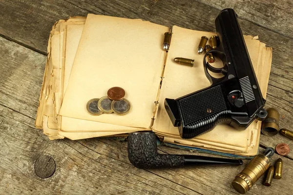 Gun and old book. Detective novel. Wooden tobacco pipe. Pistols and cartridges on the table. — Stock Photo, Image