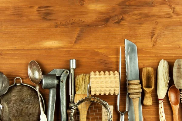 Παλιά σκεύη κουζίνας σε ένα ξύλινο ταμπλό. Πώληση εξοπλισμού κουζίνας. Εργαλεία του σεφ. — Φωτογραφία Αρχείου