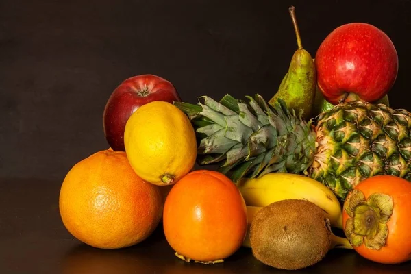 Különböző gyümölcsök, fekete konyhaasztalon. Élelmiszer-sportolók. Vitamin nátha és influenza ellen. — Stock Fotó