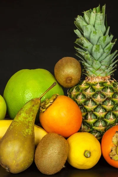 Különböző gyümölcsök, fekete konyhaasztalon. Élelmiszer-sportolók. Vitamin nátha és influenza ellen. — Stock Fotó