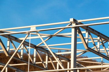 Çelik yapısı henüz tamamlanmamıştır. Metal salonları montajı. Yükseklikte çalışıyorum. Bir inşaat sahasında güneşli bir gün.