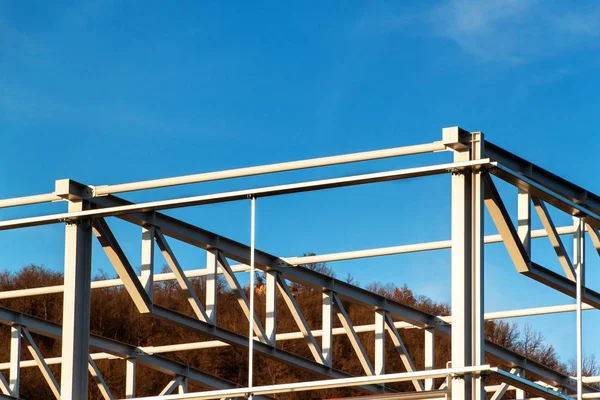 Çelik yapısı henüz tamamlanmamıştır. Metal salonları montajı. Yükseklikte çalışıyorum. Bir inşaat sahasında güneşli bir gün.