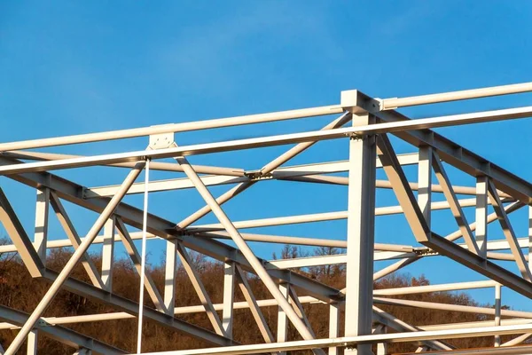 Çelik yapısı henüz tamamlanmamıştır. Metal salonları montajı. Yükseklikte çalışıyorum. Bir inşaat sahasında güneşli bir gün.