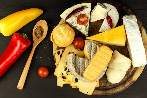 Diferentes tipos de quesos con tomate y chile en el tablero de la cocina. Preparación de alimentos saludables . — Foto de Stock