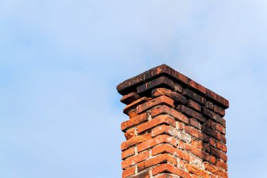 Eski tuğla baca. Arka planda gökyüzü ile baca. Çevre dostu bir müstakil ev ısıtılması.
