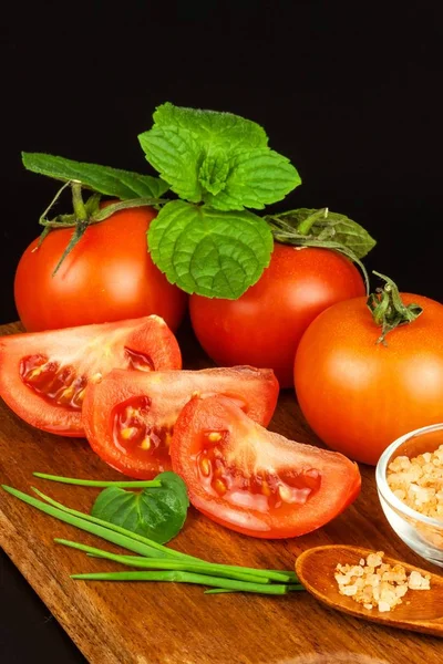 Tomater och örter på en kök ombord. Beredning av hälsosam mat. Råa grönsaker. På en svart bakgrund. — Stockfoto