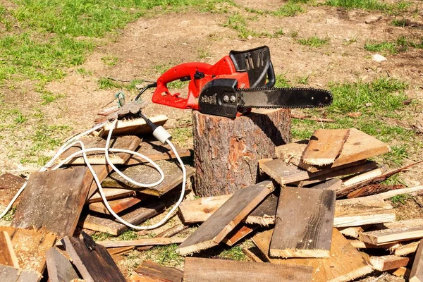 Elektriska sågar och motorsåg. Elektriska sågar kedja på bakgrunden av sågade trävaror. Begreppet bearbetning av trä för att producera bränsle. — Stockfoto