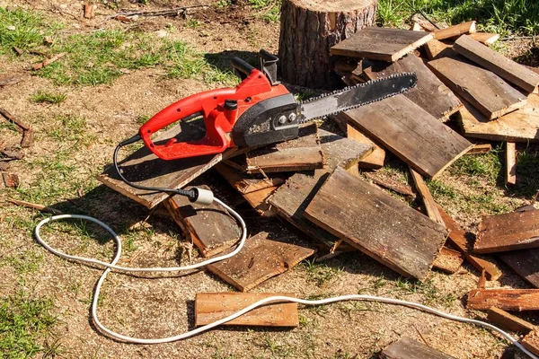 Electric saws and chainsaw. Electric saw chain on the background of sawn timber. The concept of processing wood to produce fuel. — Stock Photo, Image