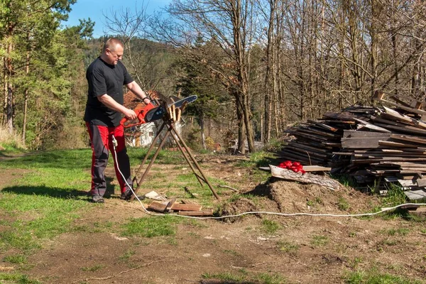 Man cutting with electric chain saw. Work on the farm. Wood preparation for heating. The woodcutter works with the saw.