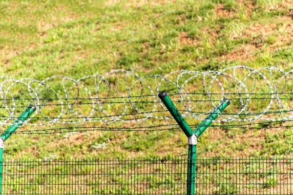 A borotvaéles szögesdrót kerítés. Őrzött terület. Katonai bázis. Erősített szúród huzal. — Stock Fotó