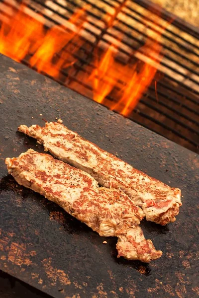 Bife grelhado num prato de granito. Preparação de carne em um fogo ao ar livre. Churrasco de verão . — Fotografia de Stock