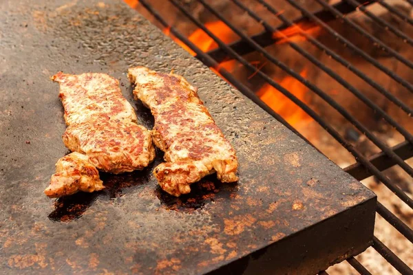 Faire griller le steak de bœuf dans une assiette de granit. Préparation de la viande sur un feu extérieur. Barbecue d'été . — Photo