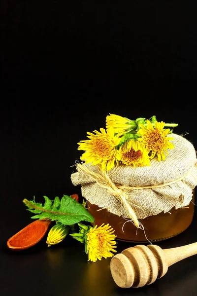 Verse paardebloem honing in een glas. De productie van honing van paardebloemen. Op een zwarte achtergrond. — Stockfoto