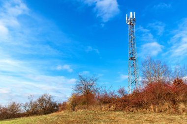 Telekomünikasyon direği mavi gökyüzüne karşı. Bayrak direğiyle sonbahar manzarası. Modern yayın teknolojisi.