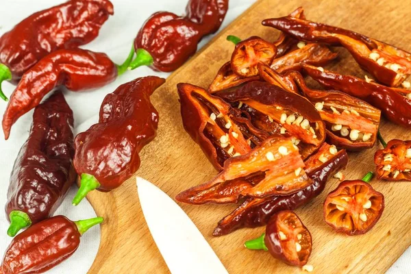 Slicing extra hot chili peppers (Bhut Jolokia Chocolate). Preparation for drying. Sale of hot spices. Healthy spices. — Stock Photo, Image