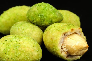 Wasabi kaplı fıstıklar tahtada. Japon Wasabi Baharatı. Siyah bir tabakta siyah fındıklı yeşil wasabi fıstığı.
