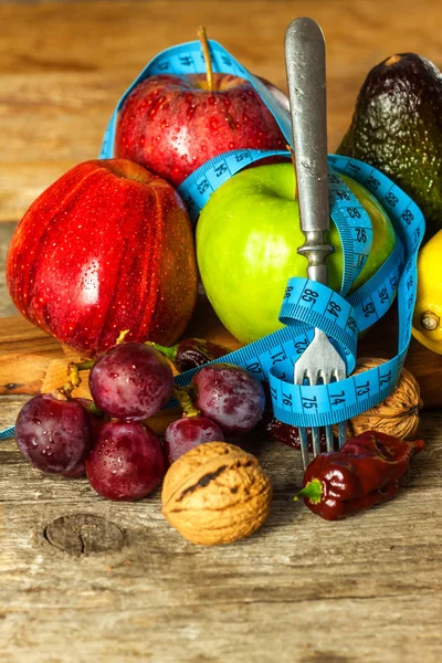 Begreppsmässig kost. Friska livsmedel. Frukt på en träskiva insvept med måttband på ett träbord. Koncept för vägning. — Stockfoto