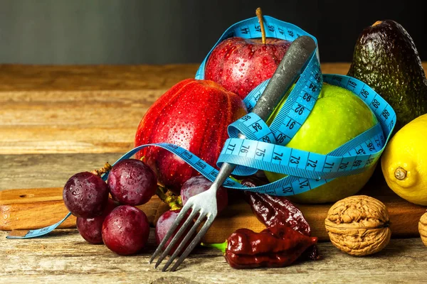 컨셉 다이어트. 건강 한 음식. 나무 탁자 위에 줄자를 씌운 나무 도마 위에 과일을 올려 놓는다. 체중 감소 개념. — 스톡 사진