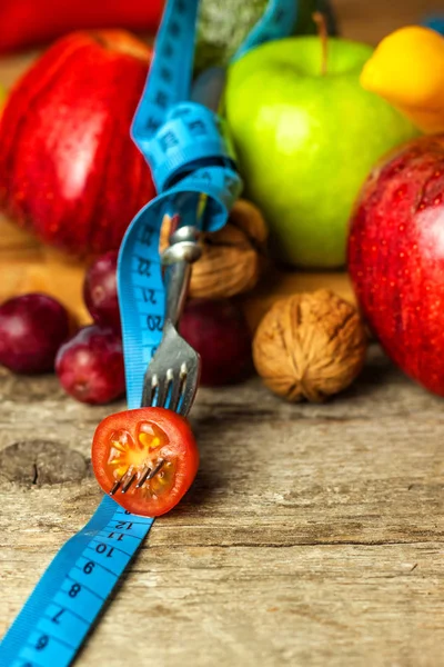 Begreppsmässig kost. Friska livsmedel. Frukt på en träskiva insvept med måttband på ett träbord. Koncept för vägning. — Stockfoto