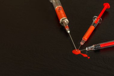 Siyah arka planda şırınga ve kan var. HIV enfeksiyonu riski var. Grip aşısı. Kan testi. Eski şırınga