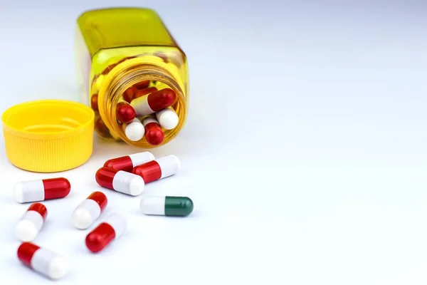 Comprimidos vermelho-brancos sobre fundo branco. Medicamentos em frasco amarelo. Conceito da indústria farmacêutica. Tratamento da doença. Suplementos vitamínicos . — Fotografia de Stock