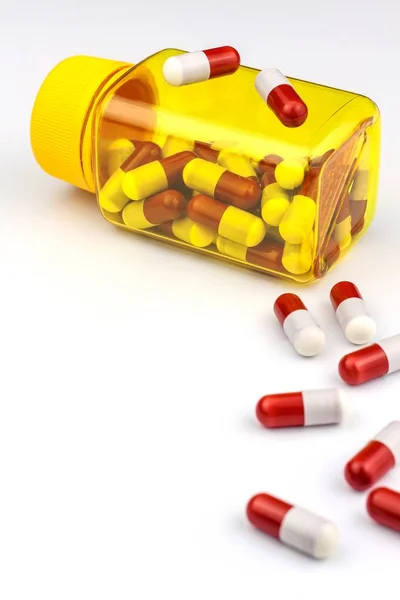 Red-white tablets on white background. Medicines in yellow jar. Pharmaceutical industry concept. Treatment of disease. Vitamin supplements. — 스톡 사진