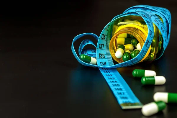 Pills with measuring tape. Weight loss concept. Obesity medications. Healthy life style. Dangerous obesity. — Stockfoto
