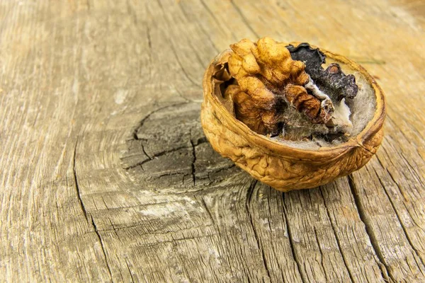 Verschimmelte Walnuss auf einem Holztisch. ungesunde Ernährung. Lebensmittelschimmel. Giftiger Schimmel. Lagerung von Nüssen. — Stockfoto