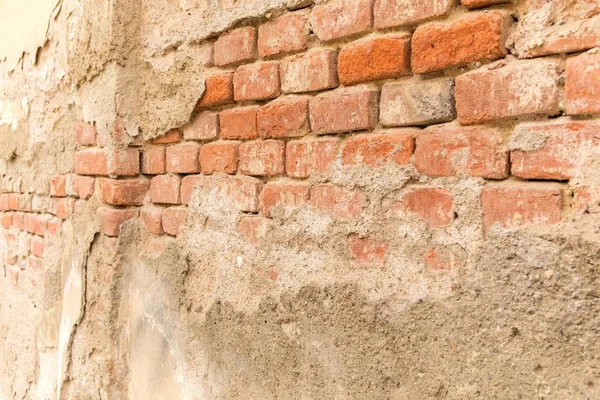 Intonaco sbucciato su un vecchio muro di mattoni. Un muro rotto. Mattoni rossi nel vecchio muro. Dettaglio della parete . — Foto Stock