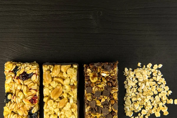 Granola bars with roasted nuts, selective focus. Oatmeal bar with nuts on black background. Nutrition for athletes. Vegetarian sweetness. — Stock Photo, Image
