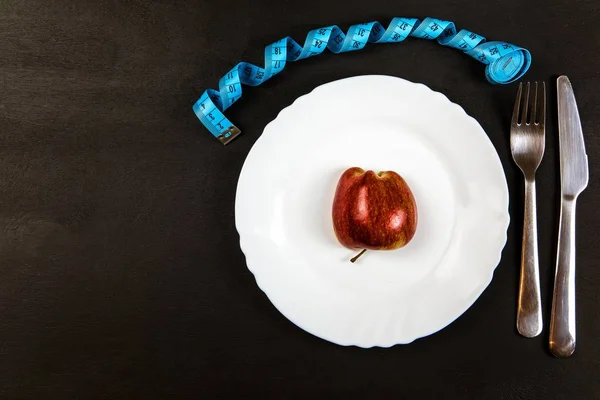 Red apple on a plate with a measuring tape. Weight loss concept. Diet food. Strict diet. — Stock Photo, Image