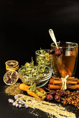 Bir fincan bitki çayı. Siyah arka planda cam kavanozlarda çeşitli bitki çayları var. Grip ve gribe karşı geleneksel ilaç.