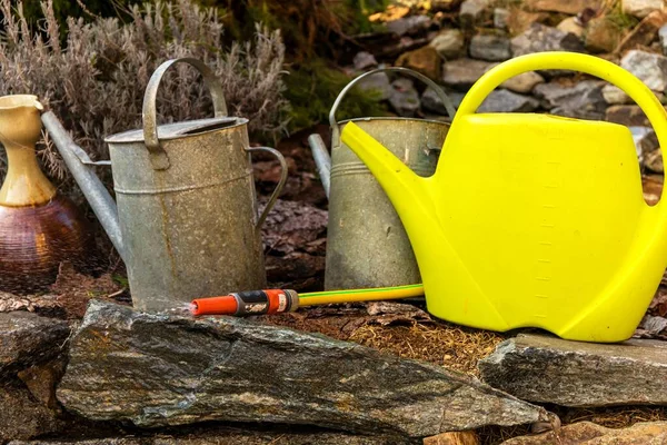 Watering cans. Watering the garden. Gardener's tools. Old metal watering cans standing on a rock in a garden. — Stock Image Watering Cans Watering Garden Gardener Tools Old Metal Watering Cans Stock Photo