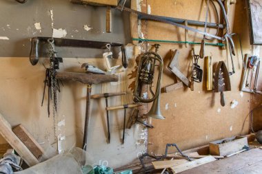 Ev atölyesindeki eski marangozluk aletleri. Tarım makinelerinin tamiri. Eski planörler ve matkaplar atölye duvarında.