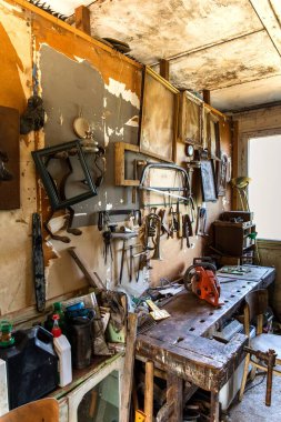 Ev atölyesindeki eski marangozluk aletleri. Tarım makinelerinin tamiri. Eski planörler ve matkaplar atölye duvarında.