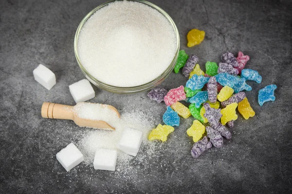 White sugar and colorful candy sweet on the dark table backgroun
