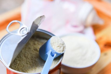 Kaşık içinde süt tozu ve tahta masa sütü şişesi. 