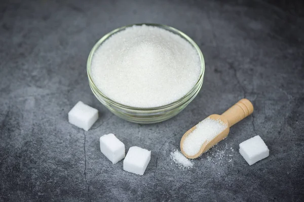 Cubos de azúcar y azúcar blanca en un tazón con fondo gris — Foto de Stock