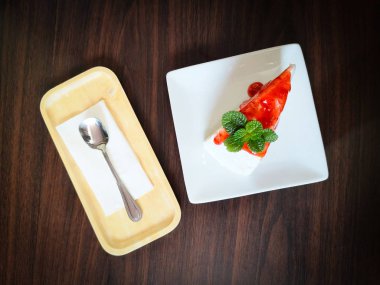 Beyaz tabakta çilek soslu pasta dilimi.