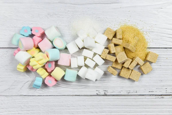 Белый сахар, кубики сахара и красочные конфеты сладкий на столе — стоковое фото